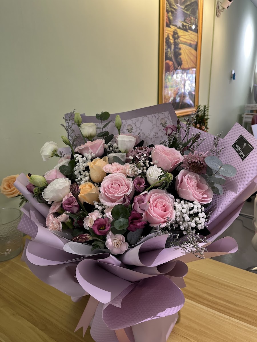 A fresh pink and cream rose bouquet in purple wrapping